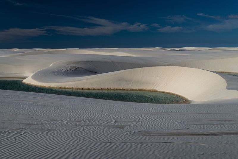 A blue freshwater lagoon among white sand dunes in Lençóis Maranhenses