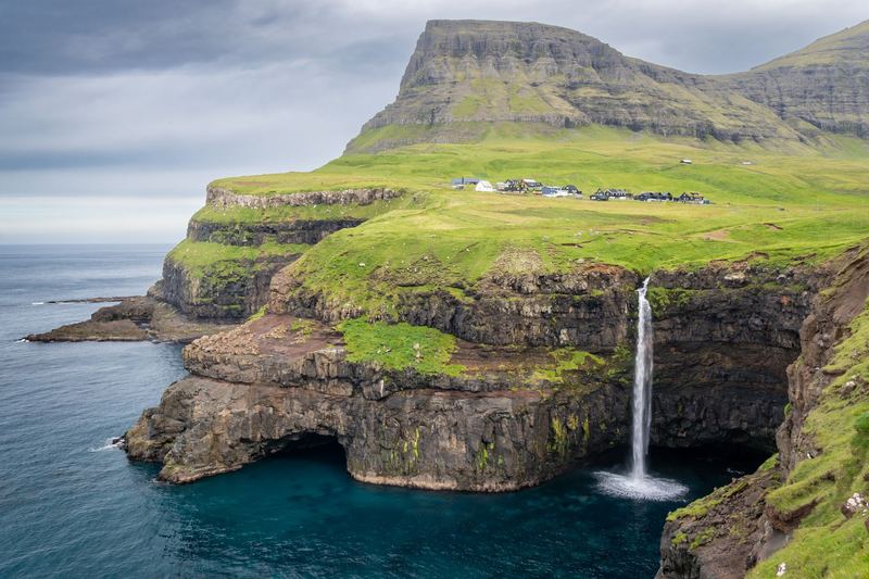 Múlafossur waterfall dropping from green cliffs into the sea at Gásadalur